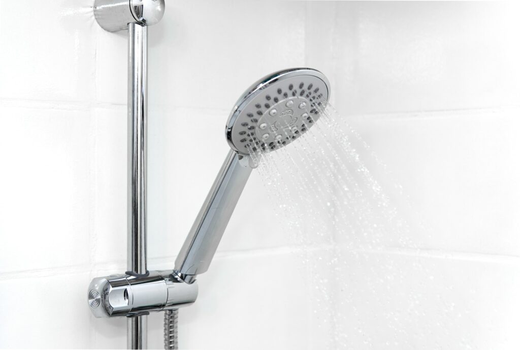 Closeup photo of shower head in bathroom with white tiles